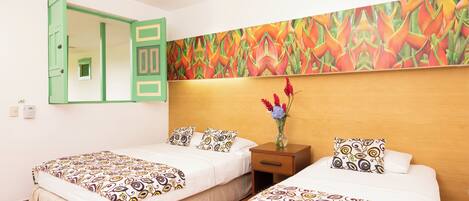 Een hotelkamer met twee bedden, een houten hoofdbord, een nachtkastje met een bloemenvaas, en een kleurrijke abstracte muurschildering.