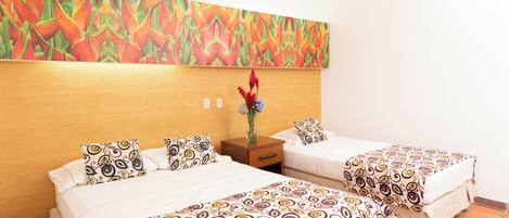 A hotel room with two beds, a wooden headboard, a nightstand, and a colorful abstract painting above the beds.