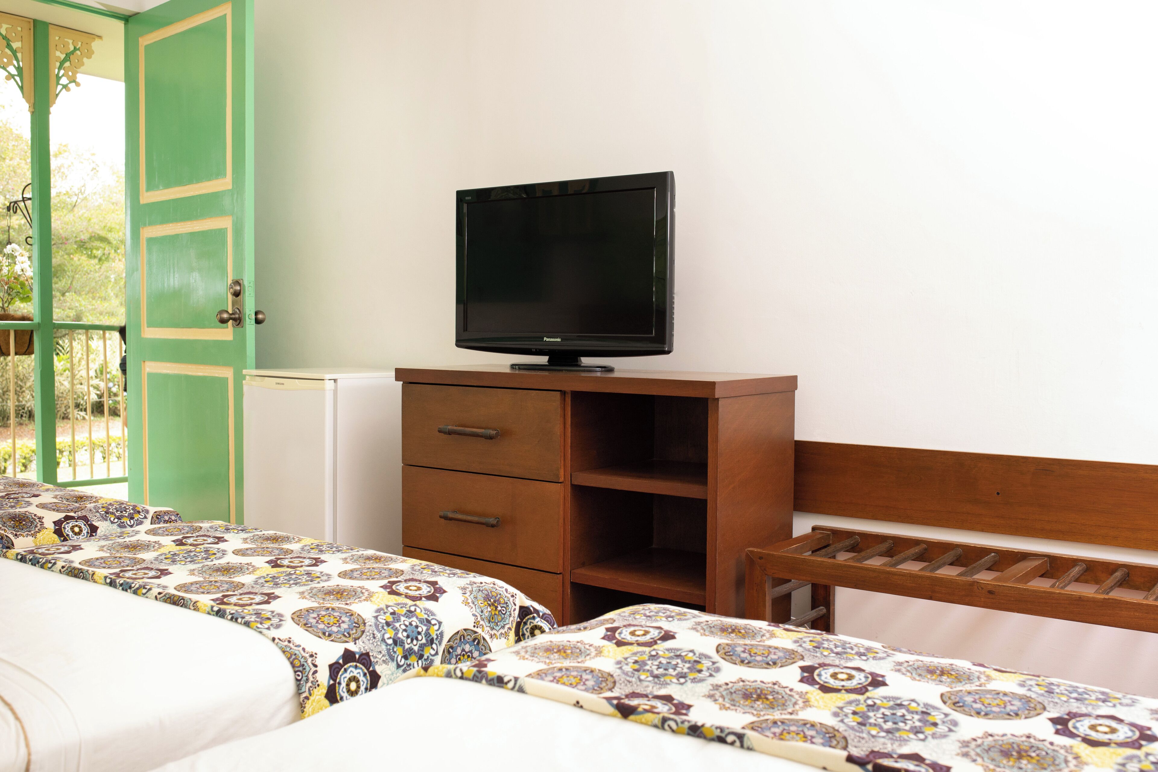 A bedroom with a bed, a dresser, and a television on a stand.