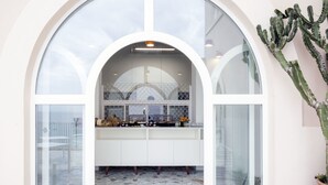 Una cocina con encimera blanca, un ventanal grande y una planta de cactus.