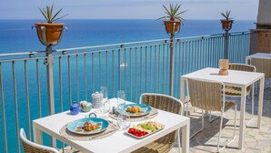 Una terraza con mesa lista para una comida, con vistas al mar.