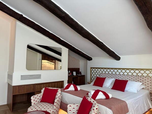 Habitación de hotel con dos camas, un espejo grande, vigas de madera y un papel tapiz estampado.