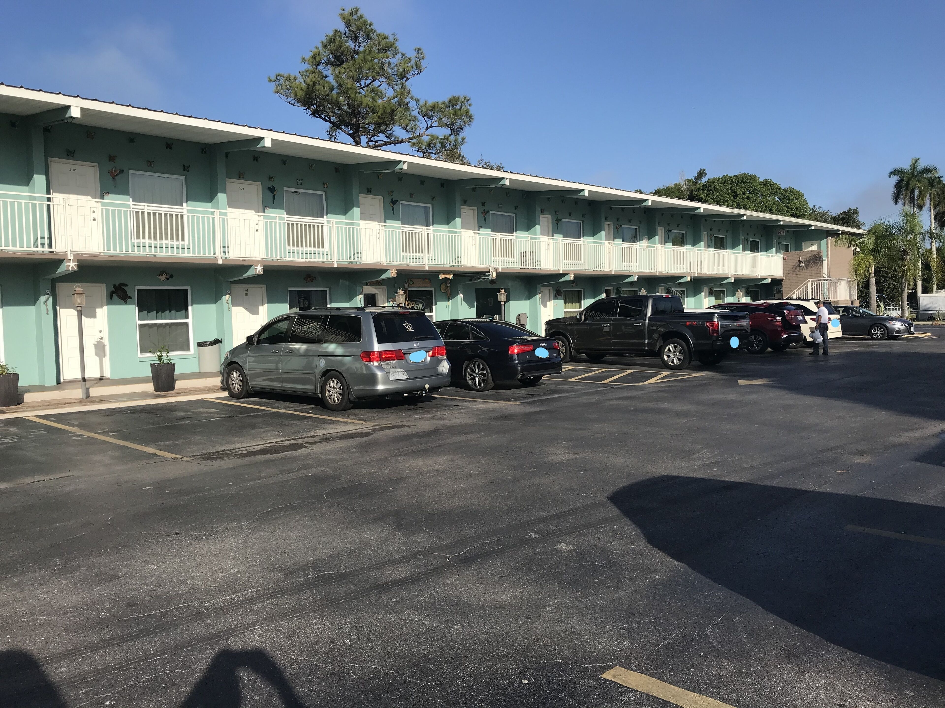 Un motel doté de nombreuses places de stationnement et d’une rangée de chambres avec balcon.
