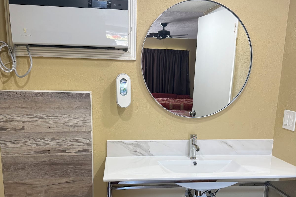 A bathroom with a white sink, mirror, and towel rack.