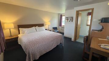 A hotel room with a bed, bedside lamps, a desk with a telephone, and a mirror.