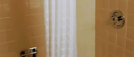 Une salle de bain avec une baignoire, une pomme de douche et un rideau.