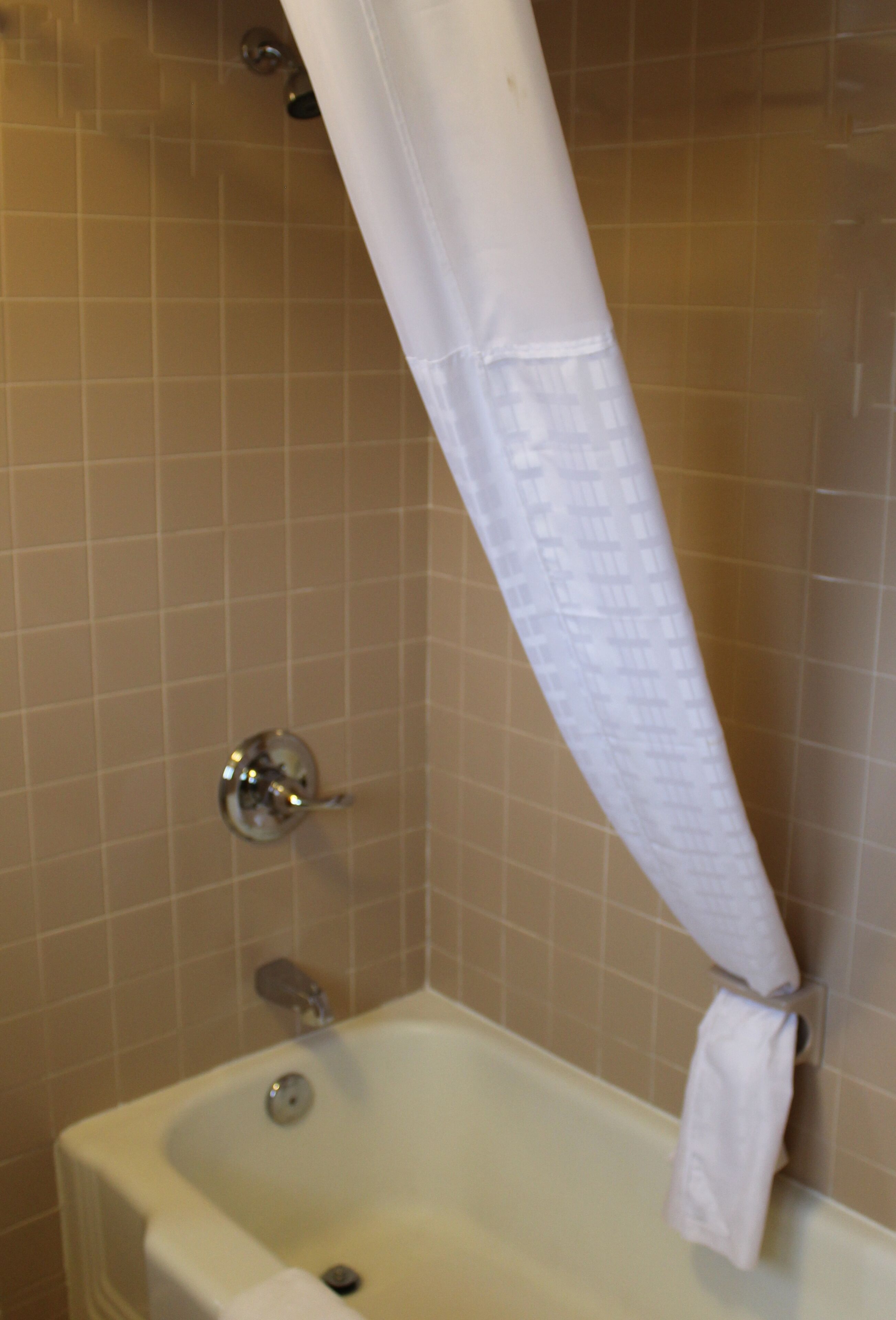 A bathroom with a bathtub, a shower curtain, and a towel rack.