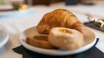 A plate with a croissant and a donut on a white tablecloth.