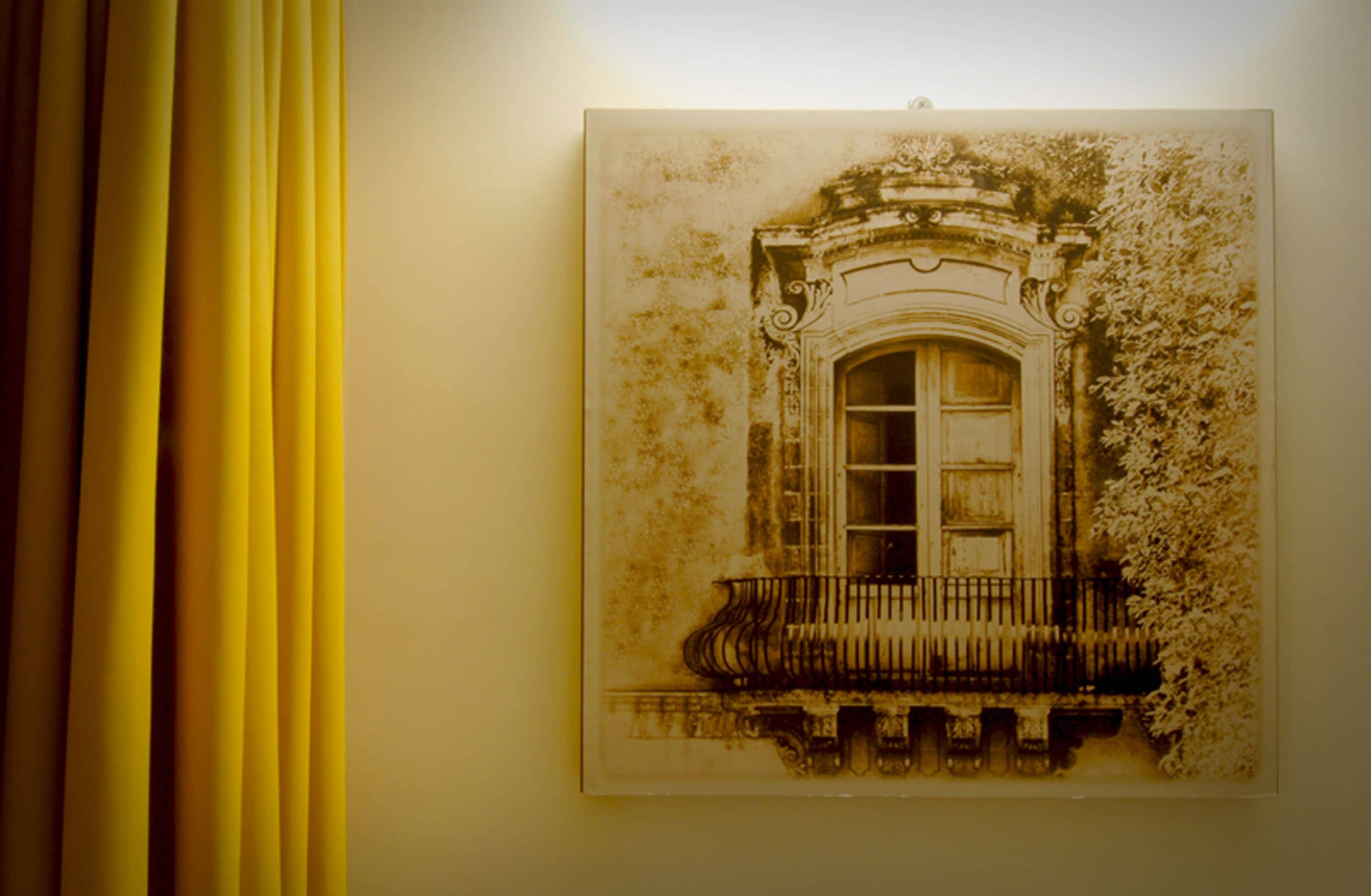 A framed architectural drawing of a building facade with ornate detailing and a balcony.