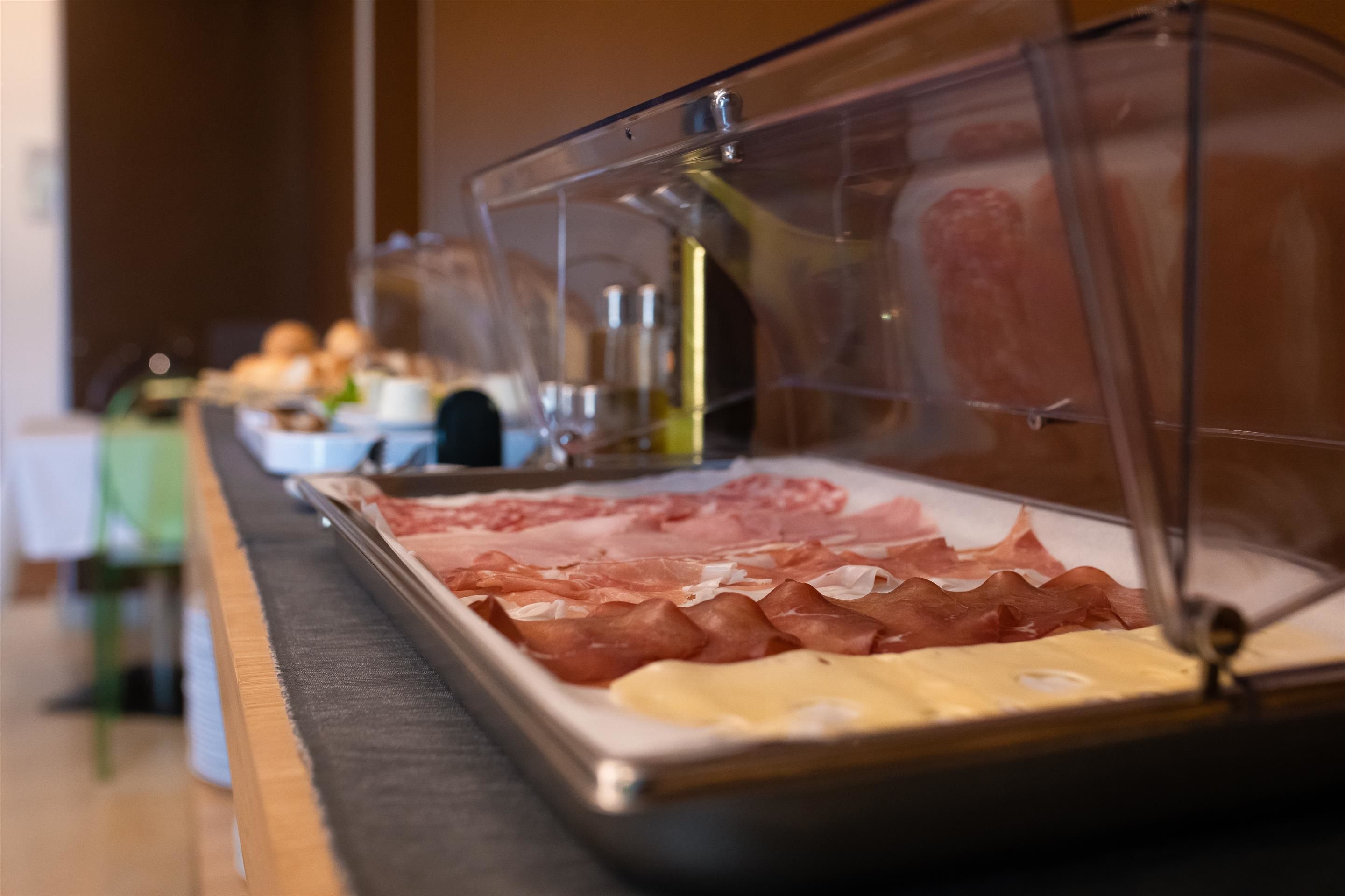 A buffet with various meats and cheeses.