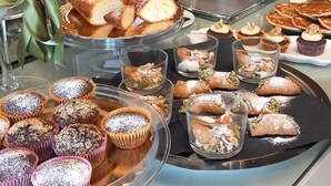 A buffet with various food items including pastries, muffins, and a coffee station.