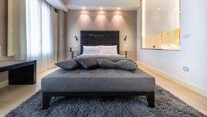 A modern bedroom with a large bed, bedside tables, a bench, and a mirror on the wall.