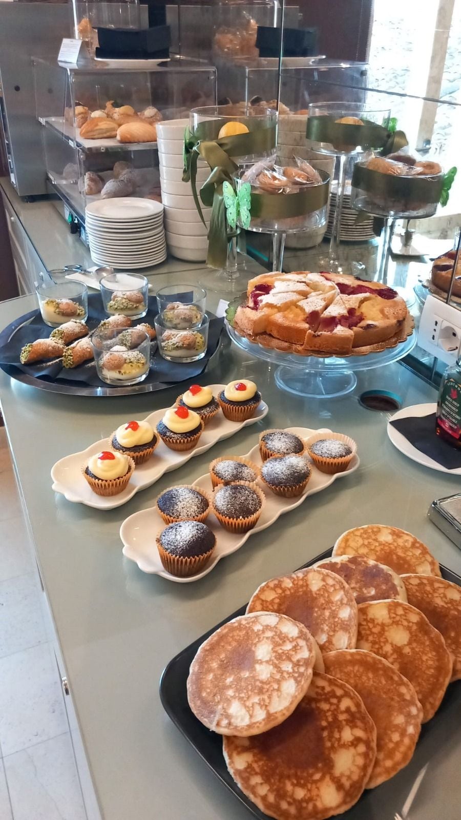 Un buffet proposant une variété de plats, notamment des pâtisseries, des petits gâteaux et des crêpes.