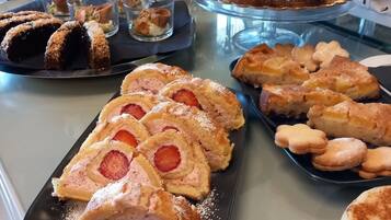 Un buffet con diverse paste e dolci, tra cui un rotolo alla fragola e altri prodotti da forno.
