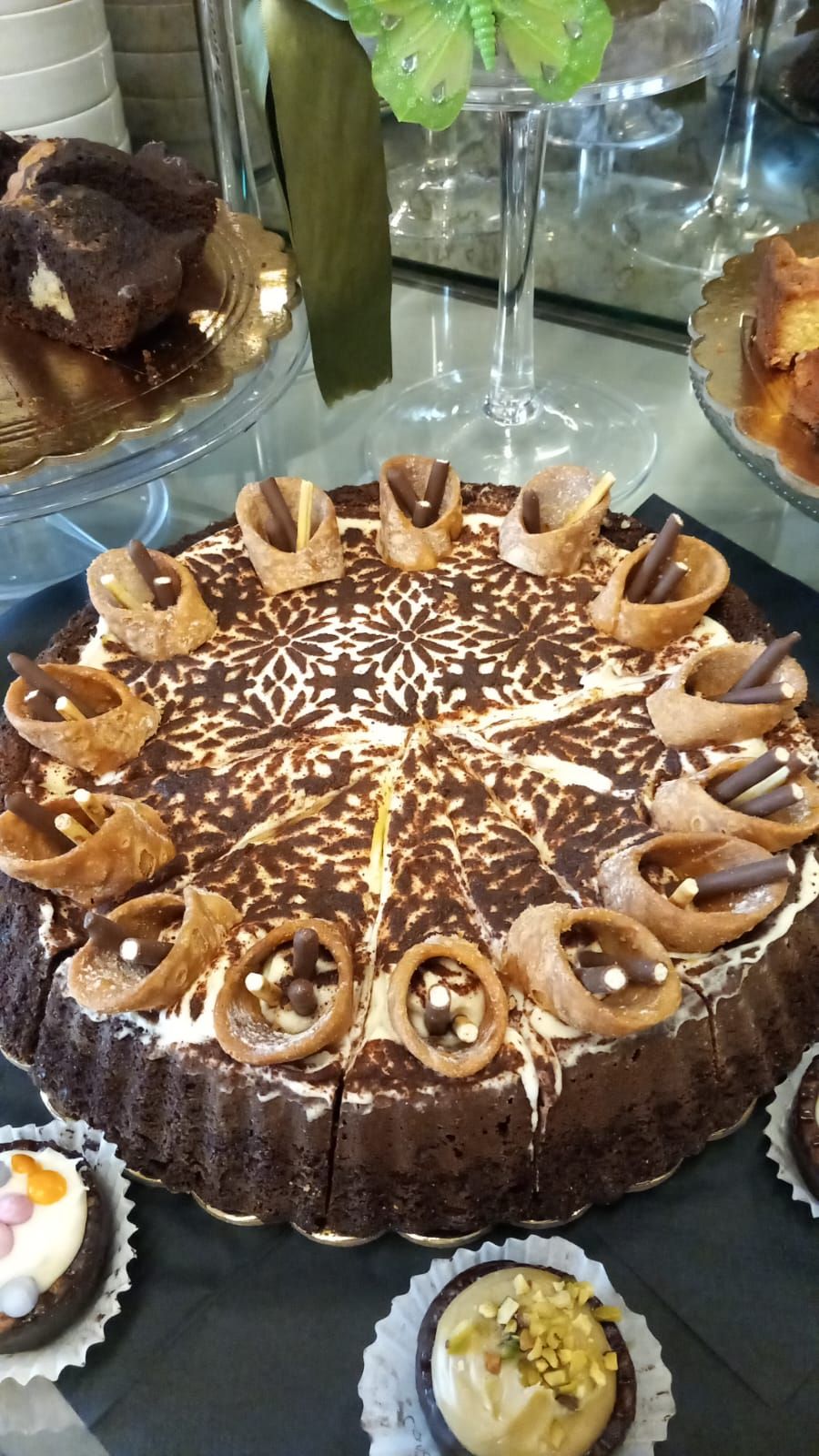 Exhibición de postres con un pastel de chocolate, adornado con anillos de chocolate decorativos y cobertura estampada.