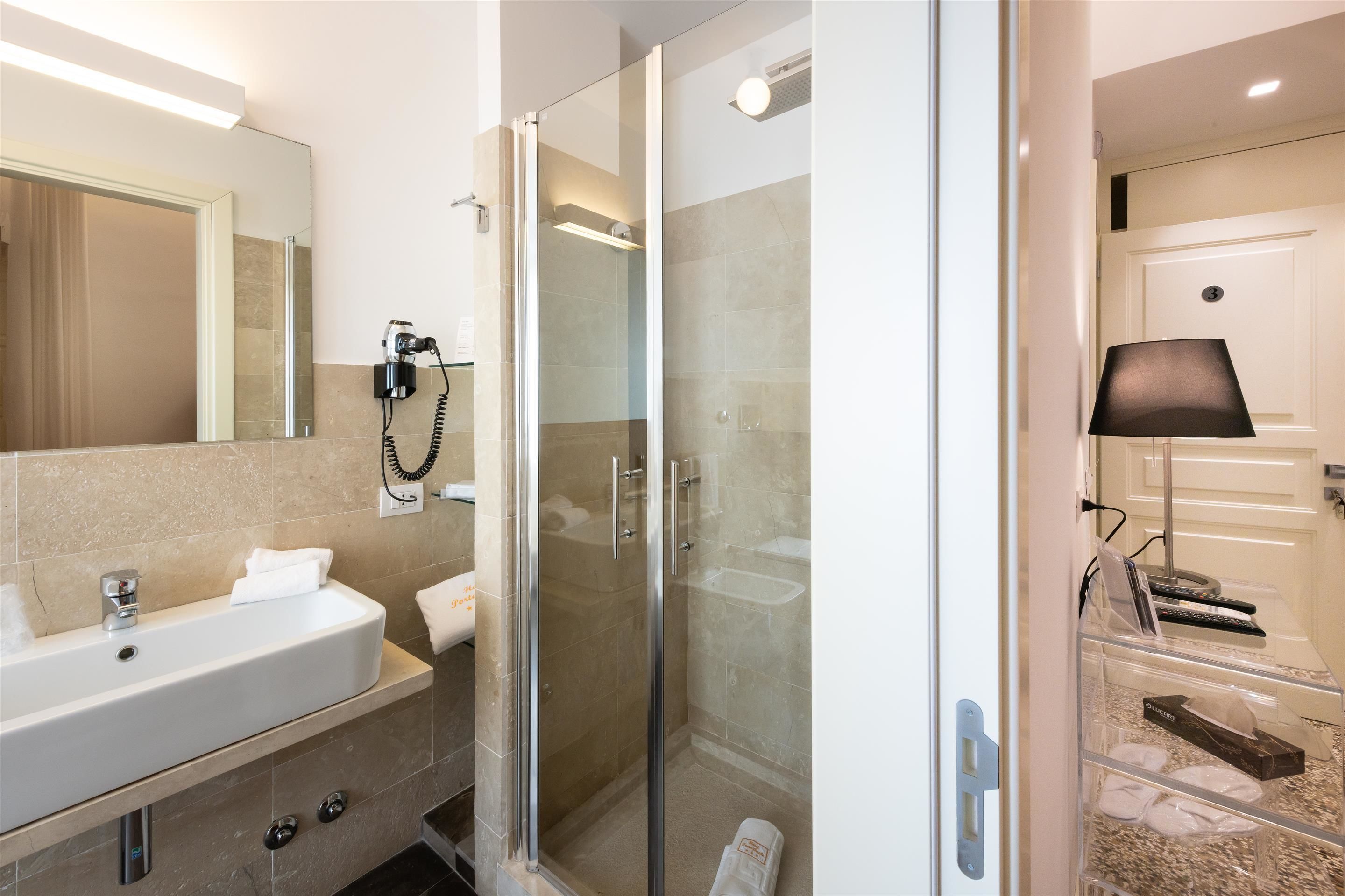A modern bathroom with a glass-enclosed shower, a sink with a mirror, and a towel rack.