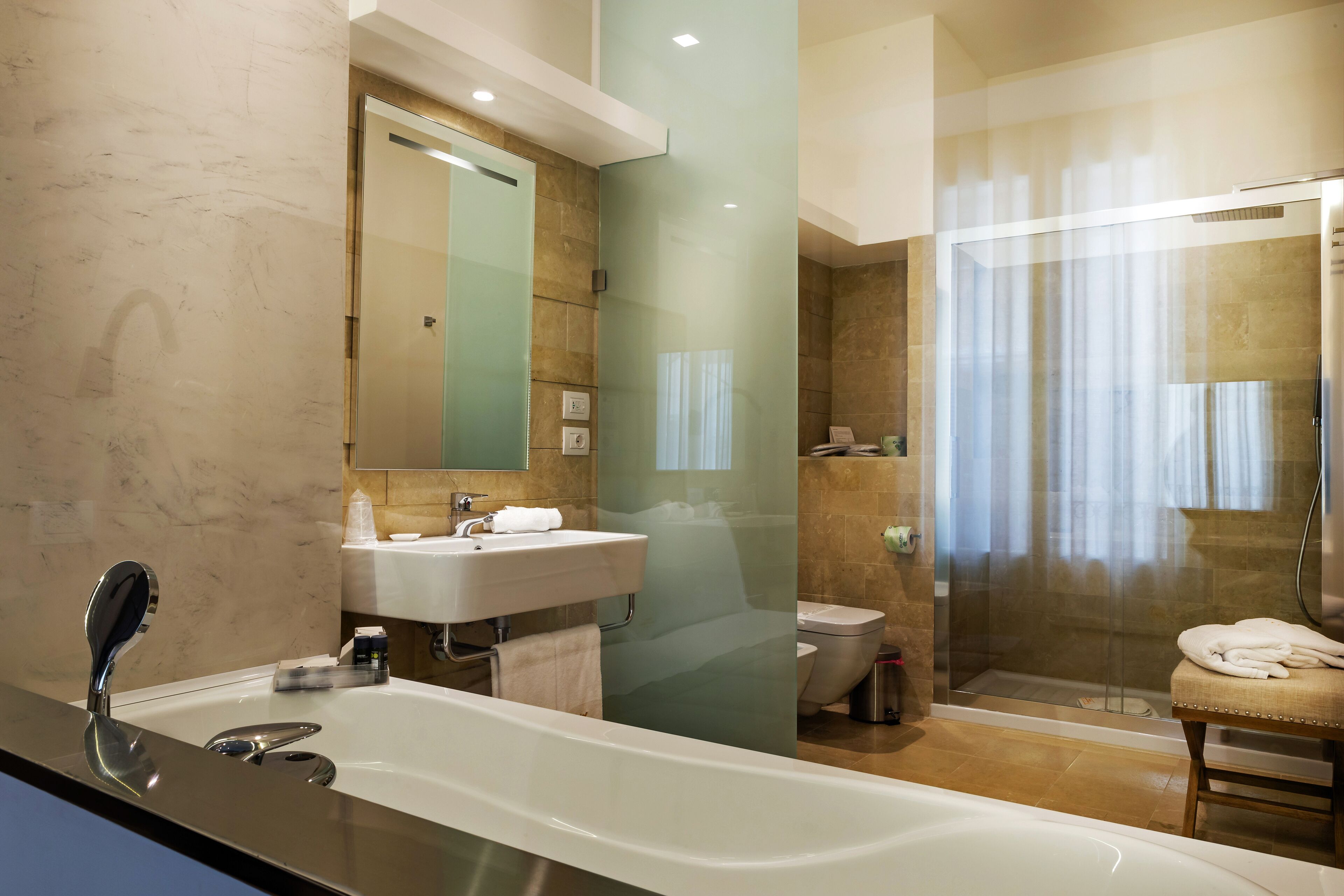 Une salle de bain moderne dotée d’une grande baignoire, d’un espace douche séparé et de toilettes séparées par une paroi en verre.