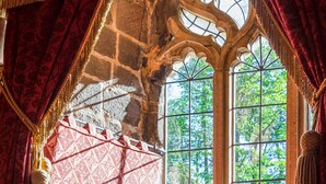 Una habitación con techo de piedra, ventanas amplias y cortinas rojas.