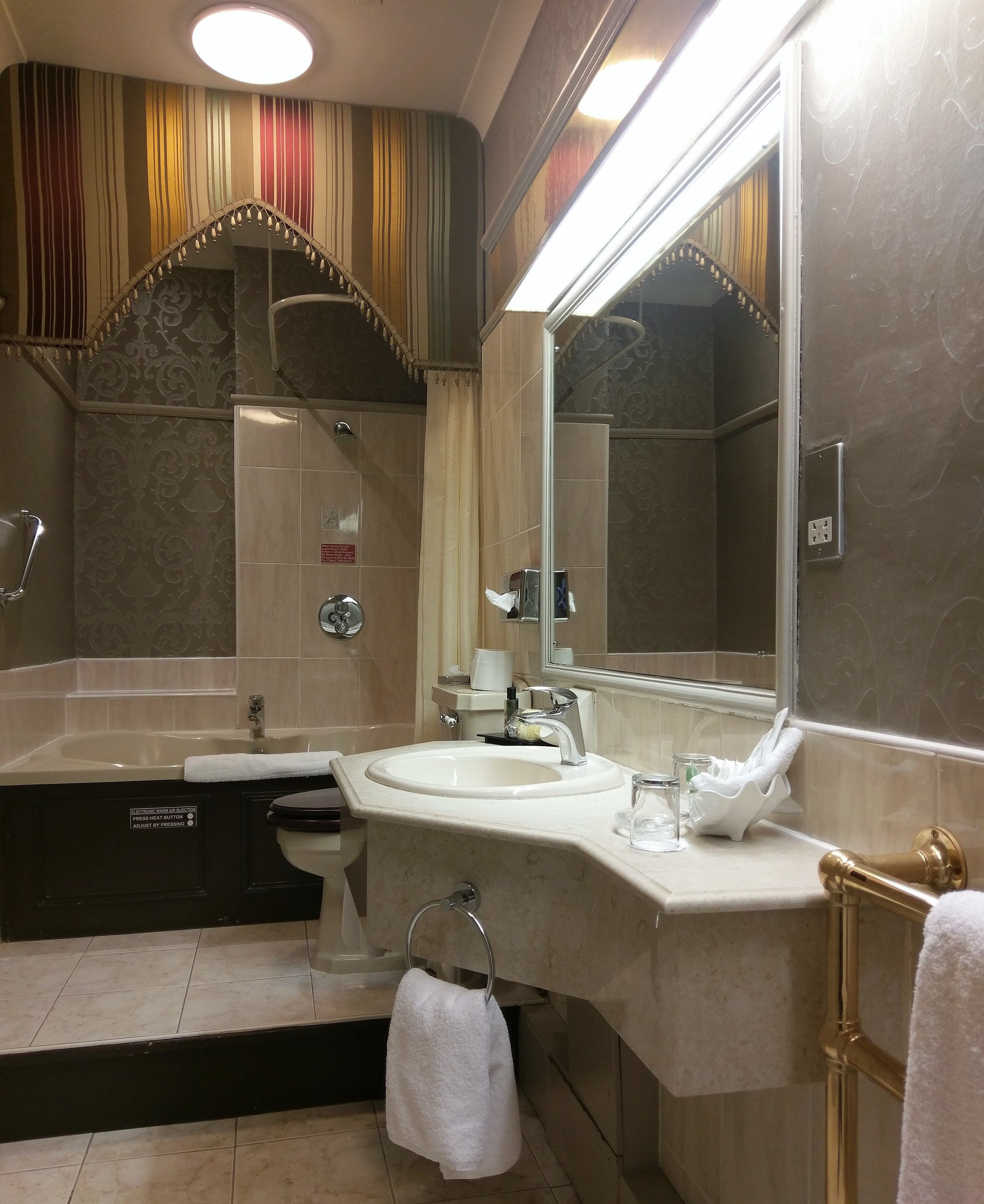 A modern bathroom with a bathtub, sink, and large mirror.