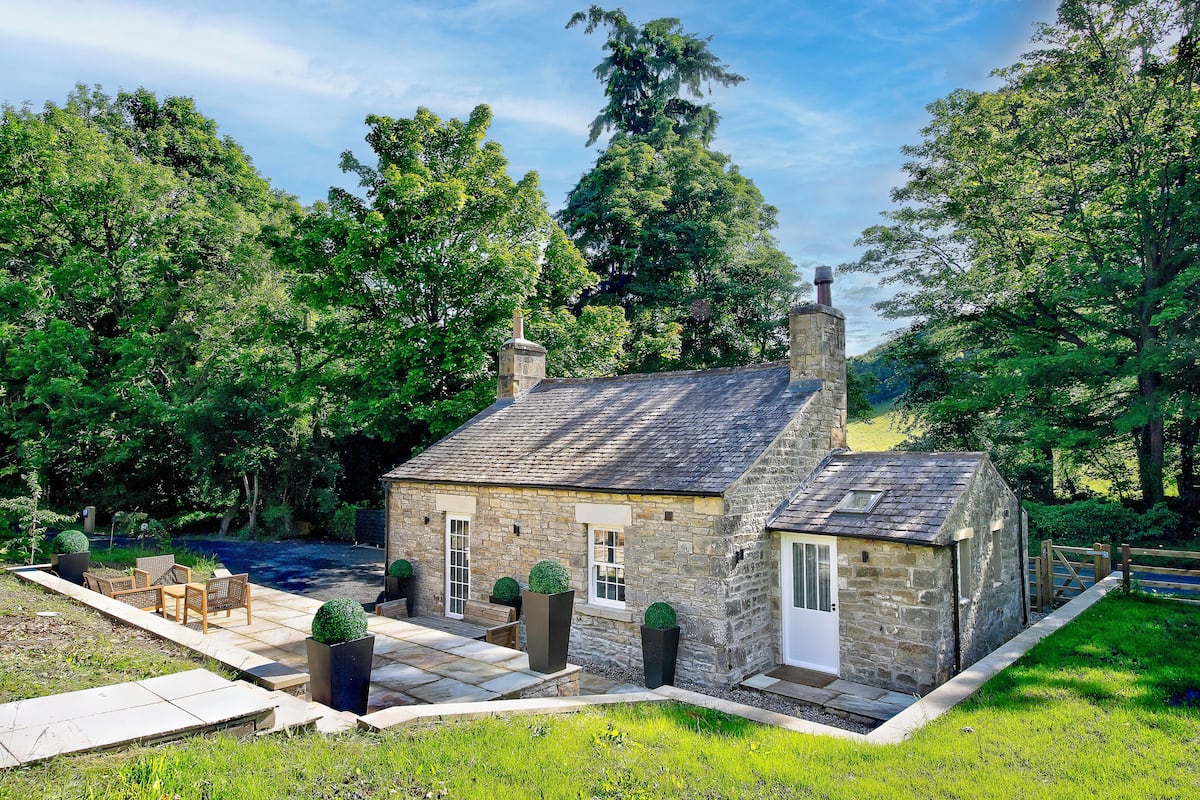 A stone house with a patio, outdoor seating, and a small garden.