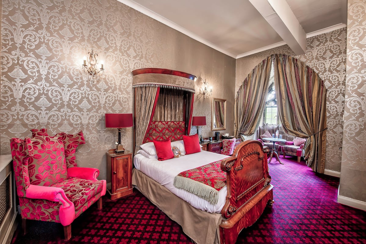 A luxurious bedroom with a large bed, ornate curtains, and a vibrant red carpet.