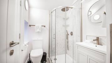 Uma casa de banho moderna com cabine de duche em vidro, sanita e lavatório com espelho.