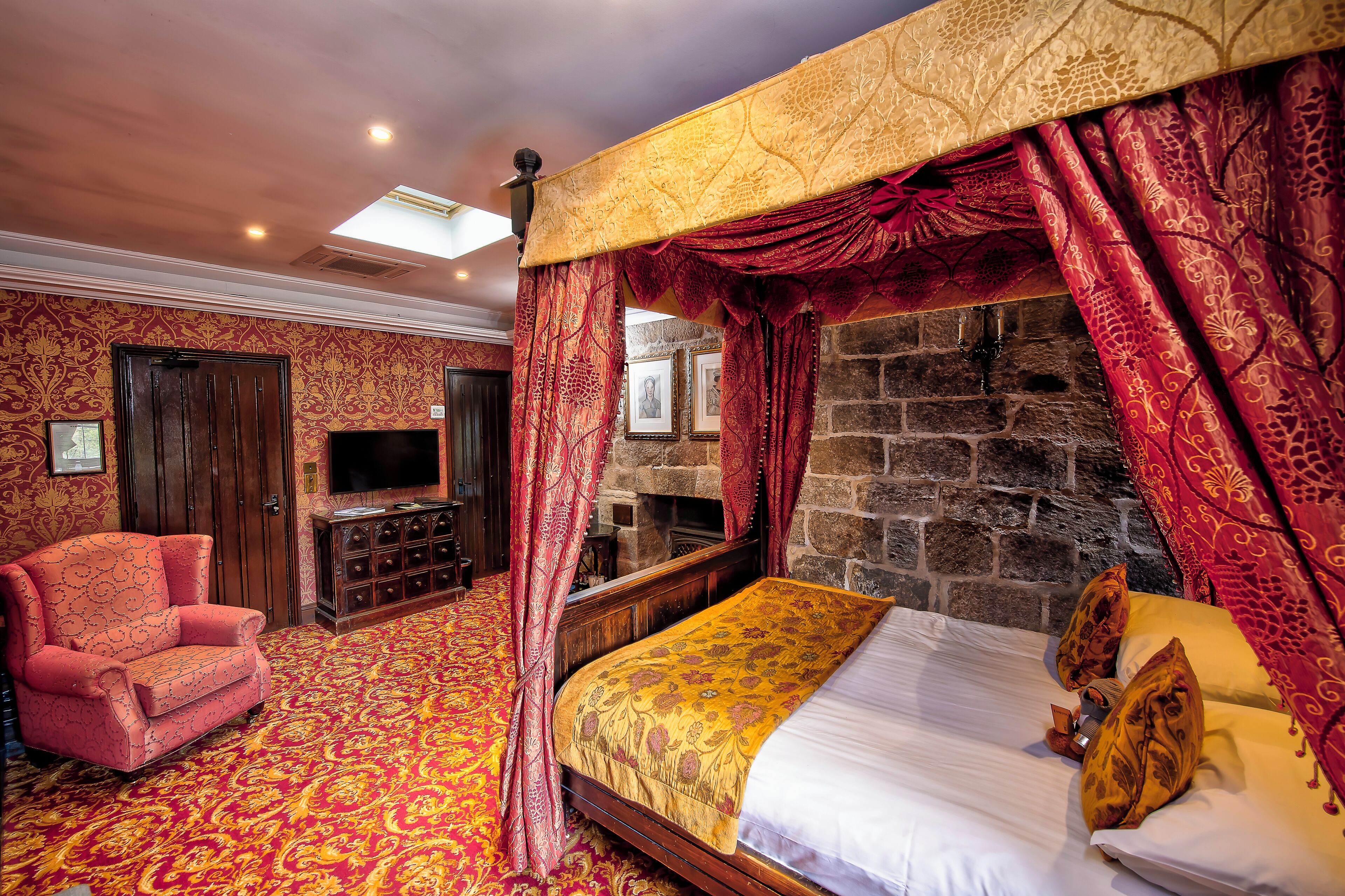 Una habitación con cama, una silla y una pared de piedra.