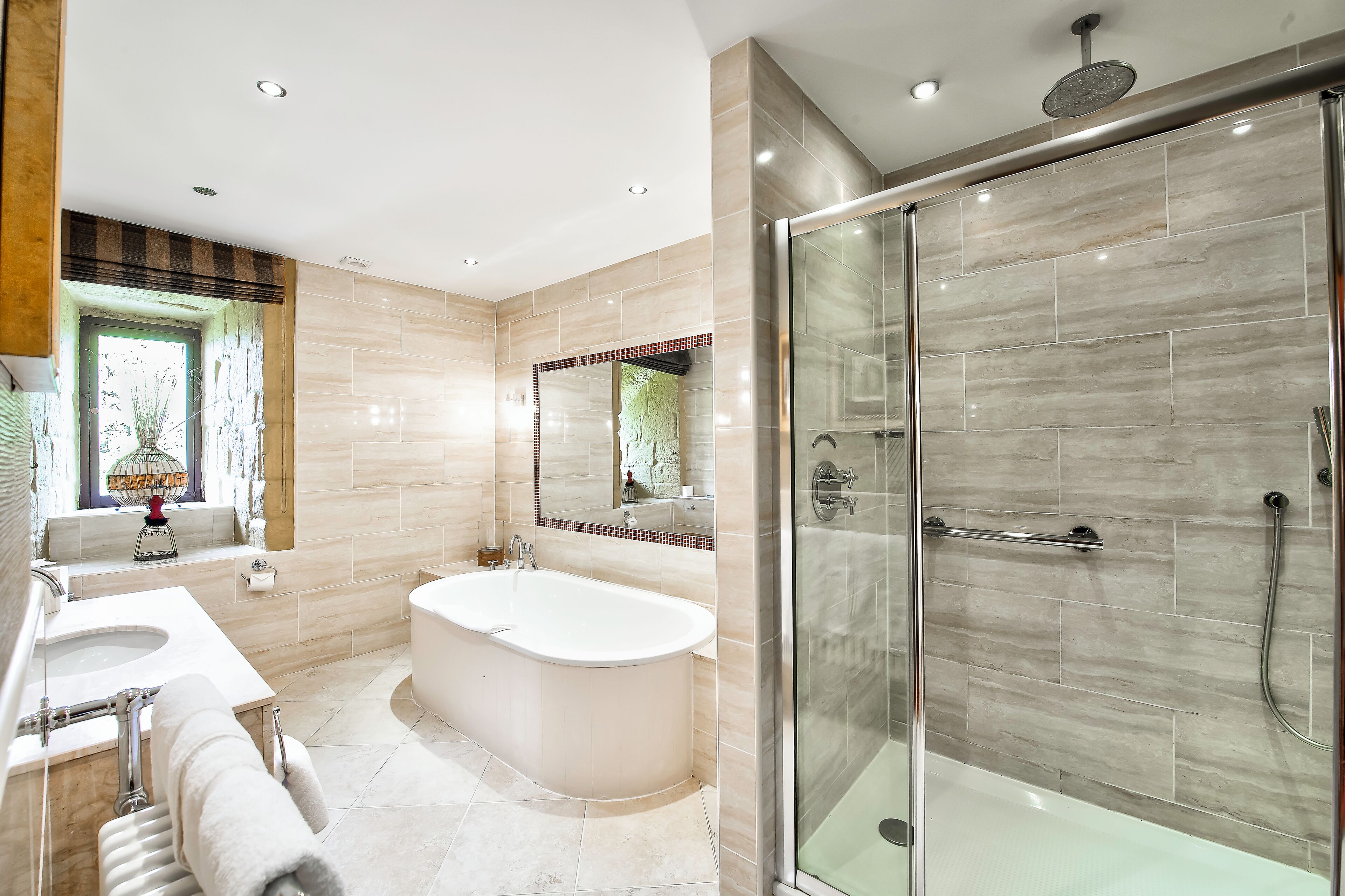 Une salle de bain moderne avec une baignoire, une douche à l’italienne et un grand miroir.