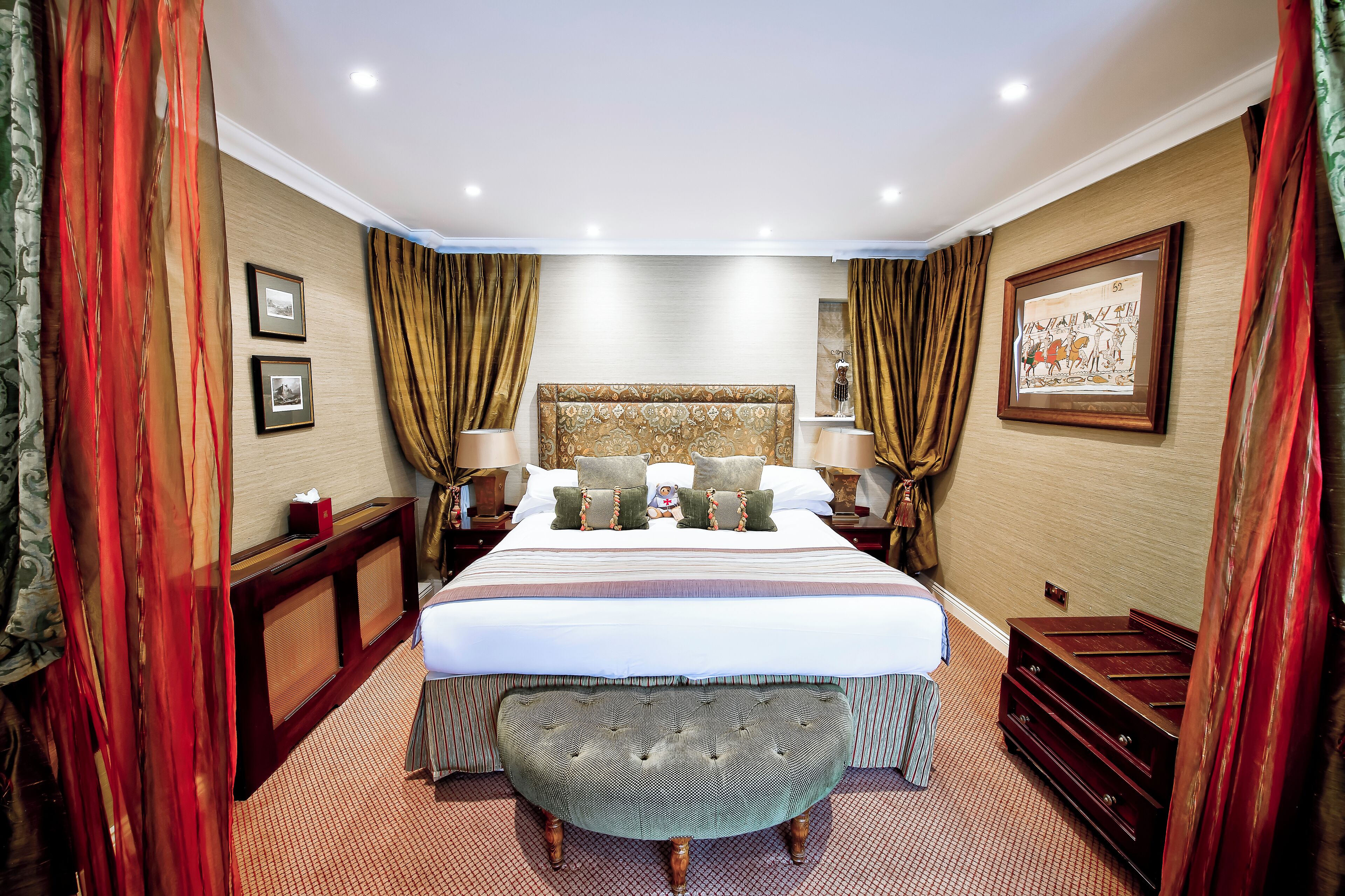 Una habitación de hotel espaciosa con una cama grande, un banco y un aparador.