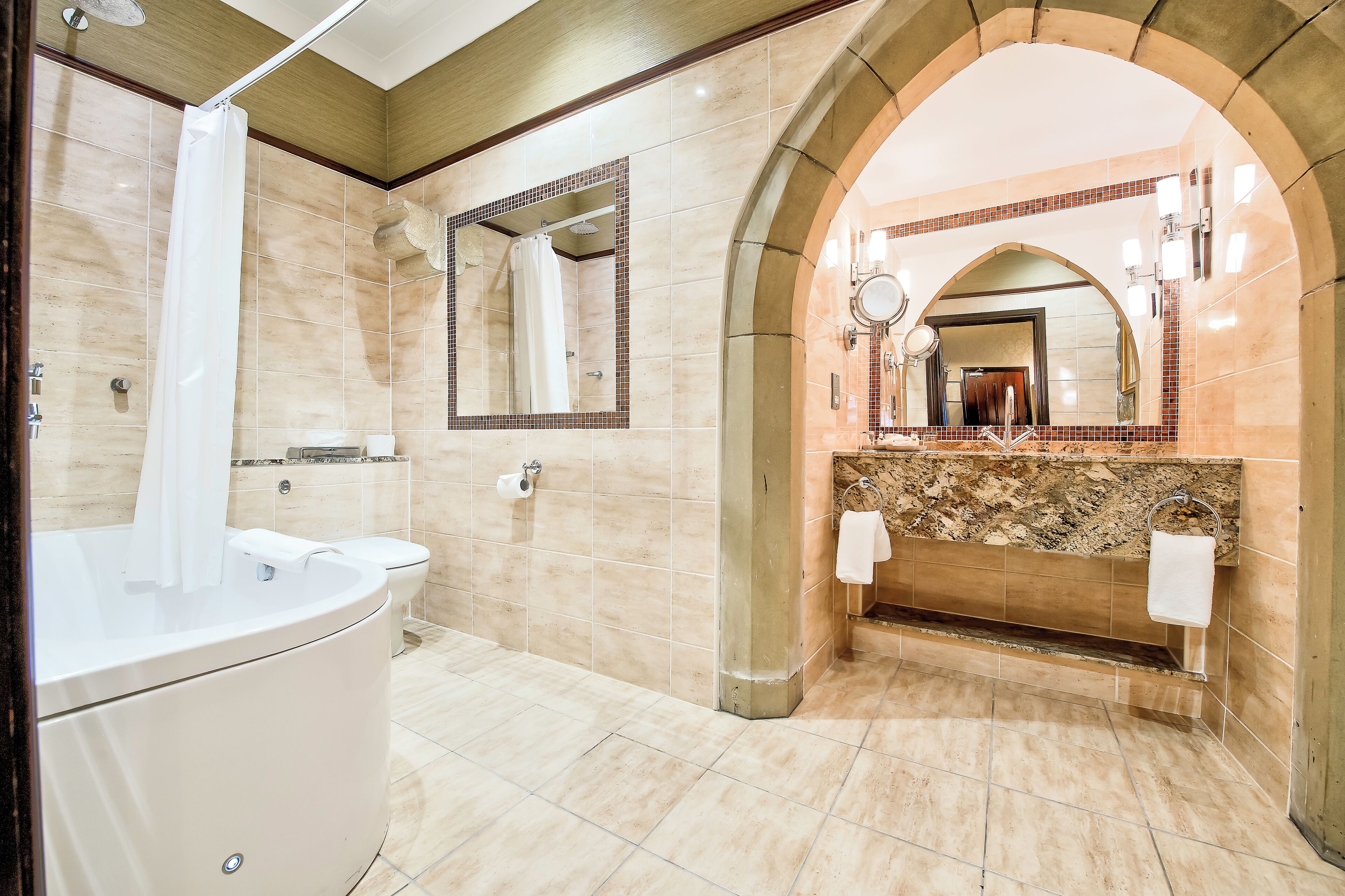 Un baño moderno con bañera, inodoro, lavabo y tocador con espejo.