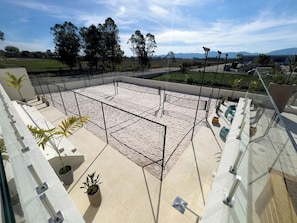 An outdoor area with a sandy floor, surrounded by a metal fence, and includes potted plants and seating areas. - Intercity Pátio Pinda Hotel & Resort (Pindamonhangaba)