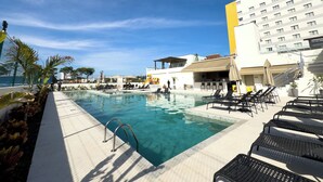 Una piscina con sillas de descanso y un edificio de varios pisos.