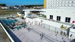 A rooftop pool area with lounge chairs and umbrellas, a covered seating area, and a view of the surrounding buildings. - Intercity Pátio Pinda Hotel & Resort (Pindamonhangaba)