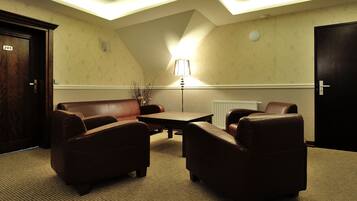 A room with a brown leather sofa set, a small table, and a lamp.