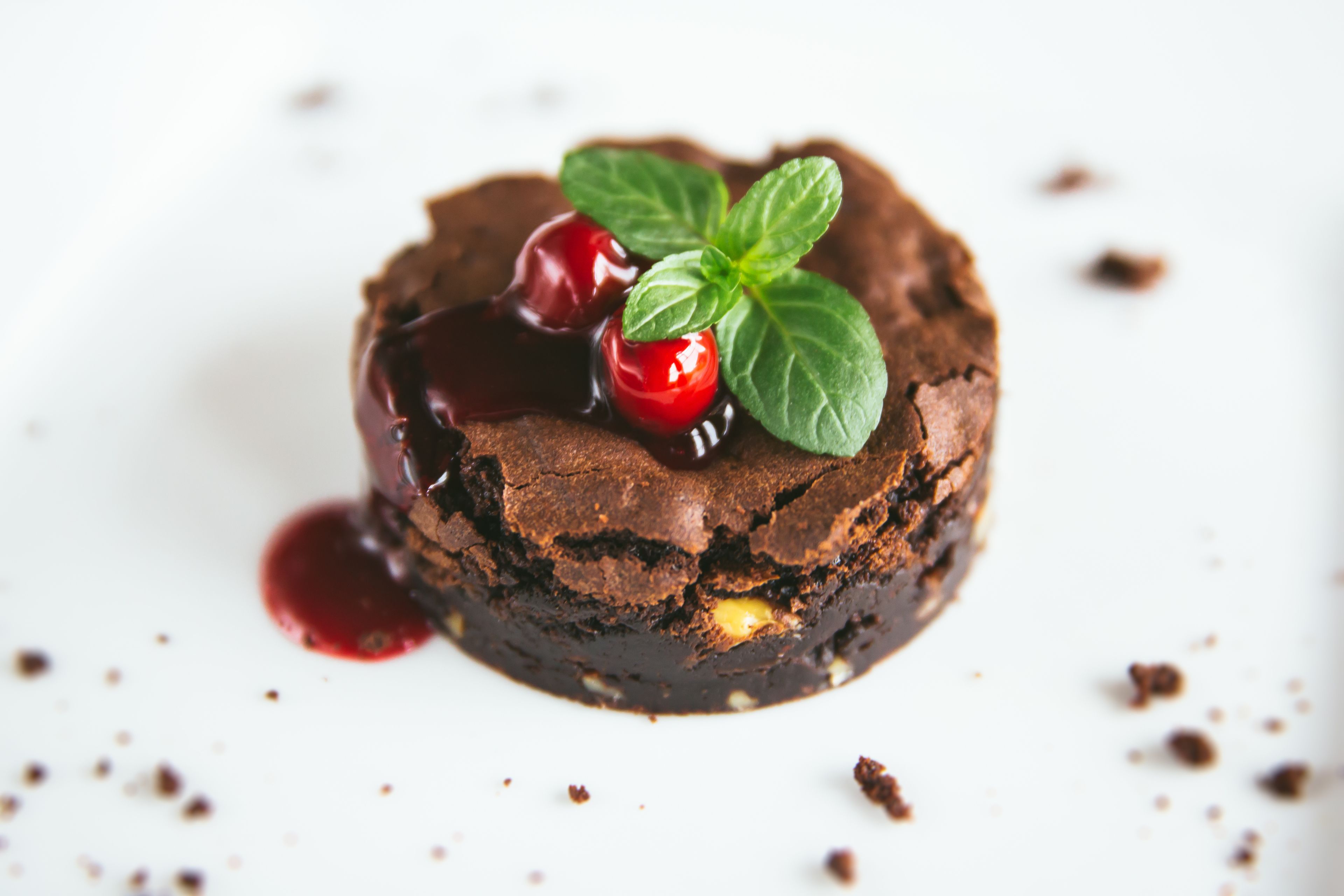Un dessert composé de gâteau au chocolat, de cerises et de feuilles de menthe.