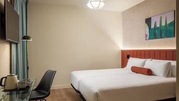 Habitación de hotel con cama, escritorio con silla, televisor y un cuadro en la pared.