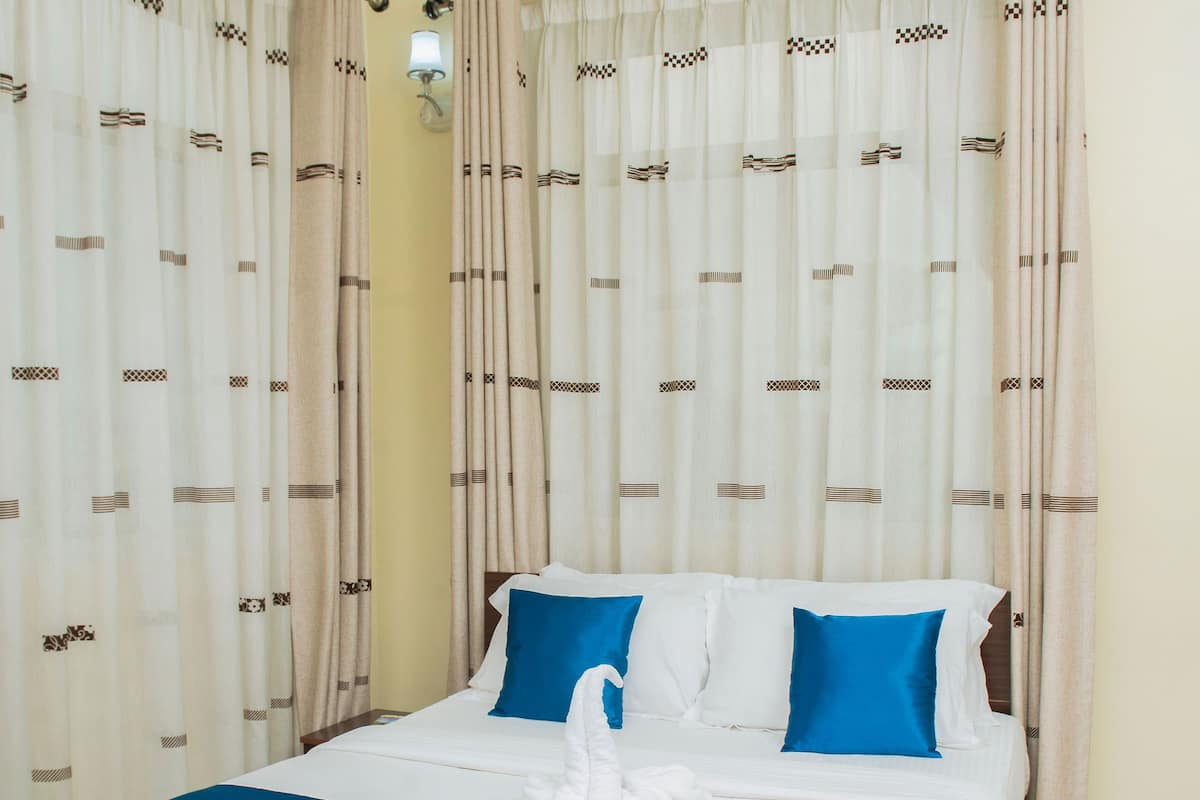 A neatly made bed with blue and white bedding, a white towel, and a decorative item on the bed.