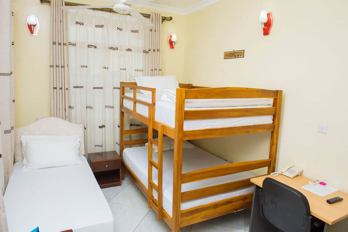A room with bunk beds, a desk with a chair, a telephone, and a wall-mounted light fixture.