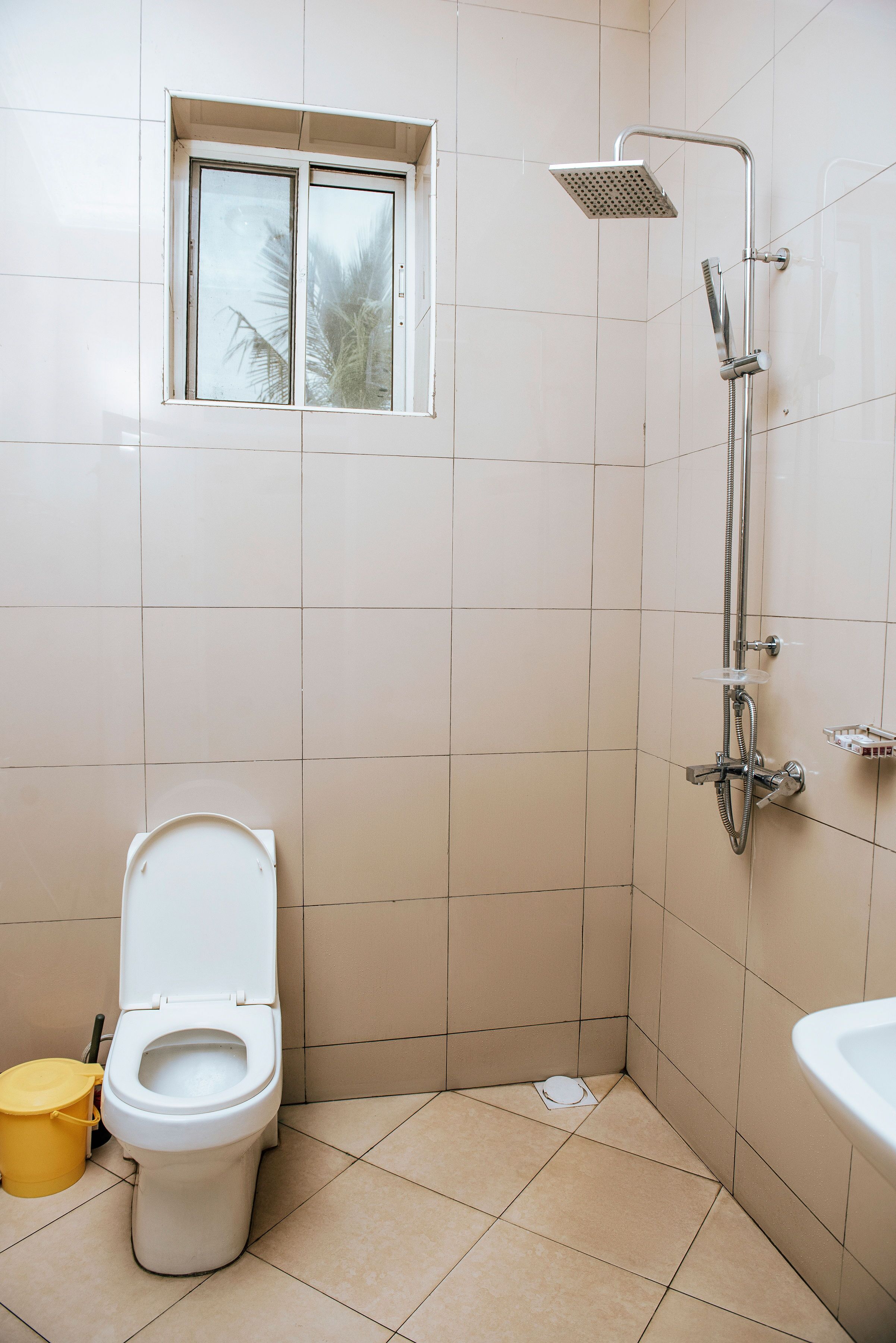 A bathroom with a toilet, a window, and a shower.