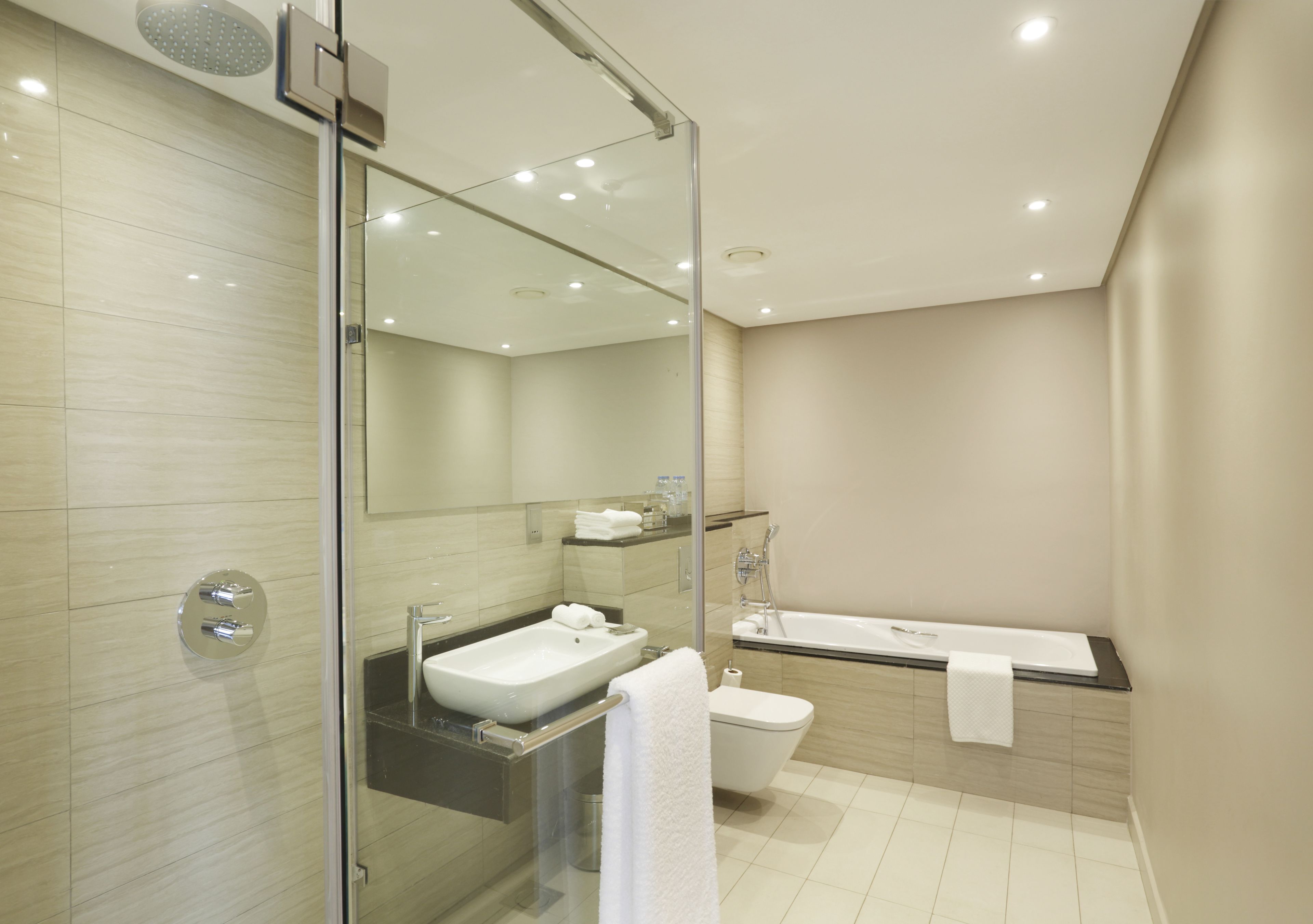 Un baño moderno con ducha envuelta en cristal, lavamanos, inodoro y bañera.