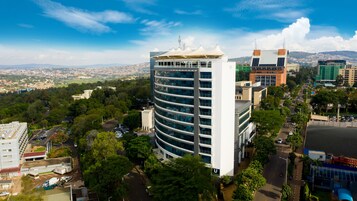 A modern hotel with a curved facade, multiple floors, and a rooftop terrace.