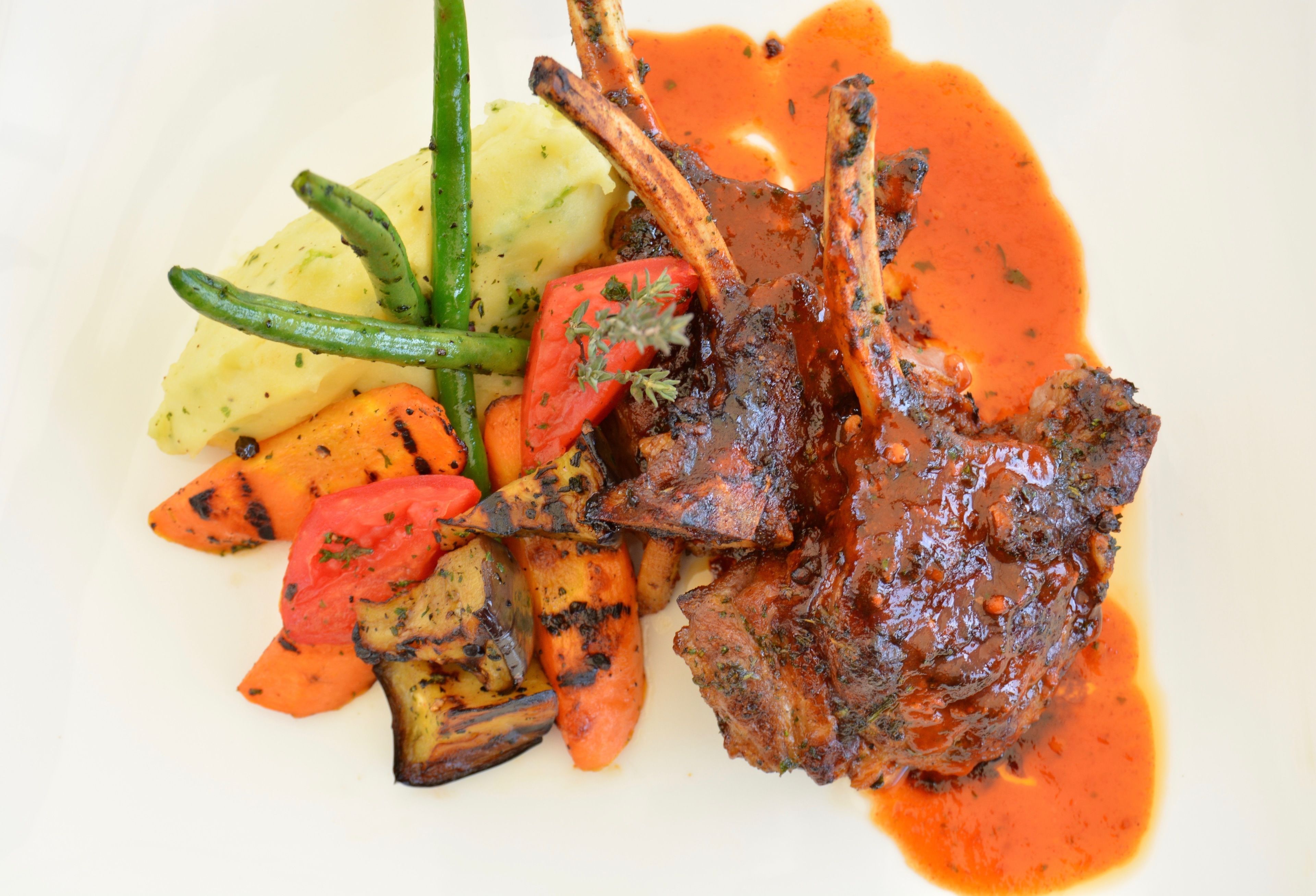A plate with grilled vegetables, a meat dish, and a sauce.