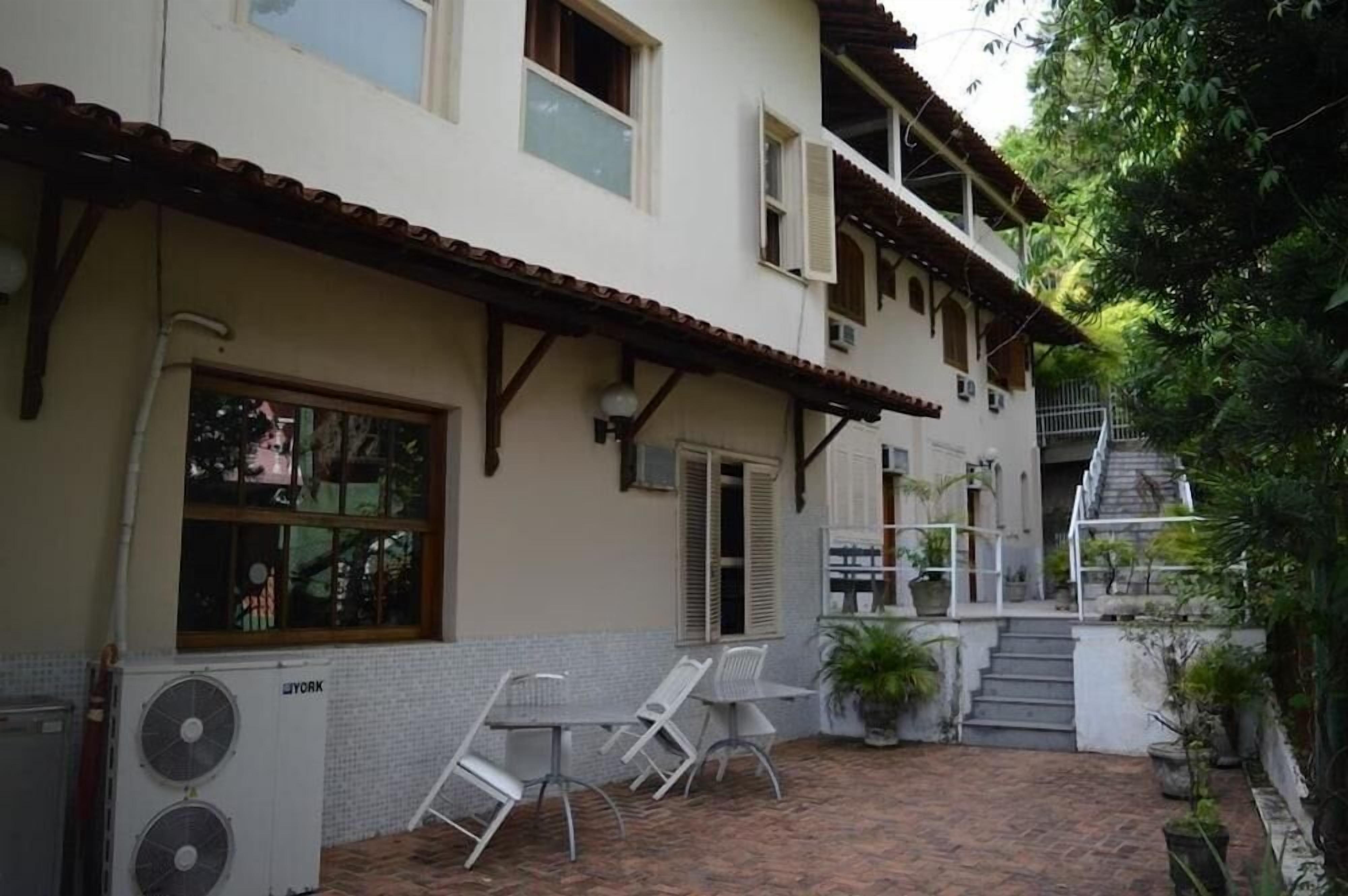 A two-story building with a tiled patio, outdoor seating, and a staircase leading to an upper level.