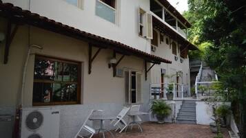 A two-story building with a tiled patio, outdoor seating, and a staircase leading to an upper level.