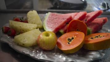 A fruit platter with pineapple, watermelon, apple, and papaya on a silver plate.