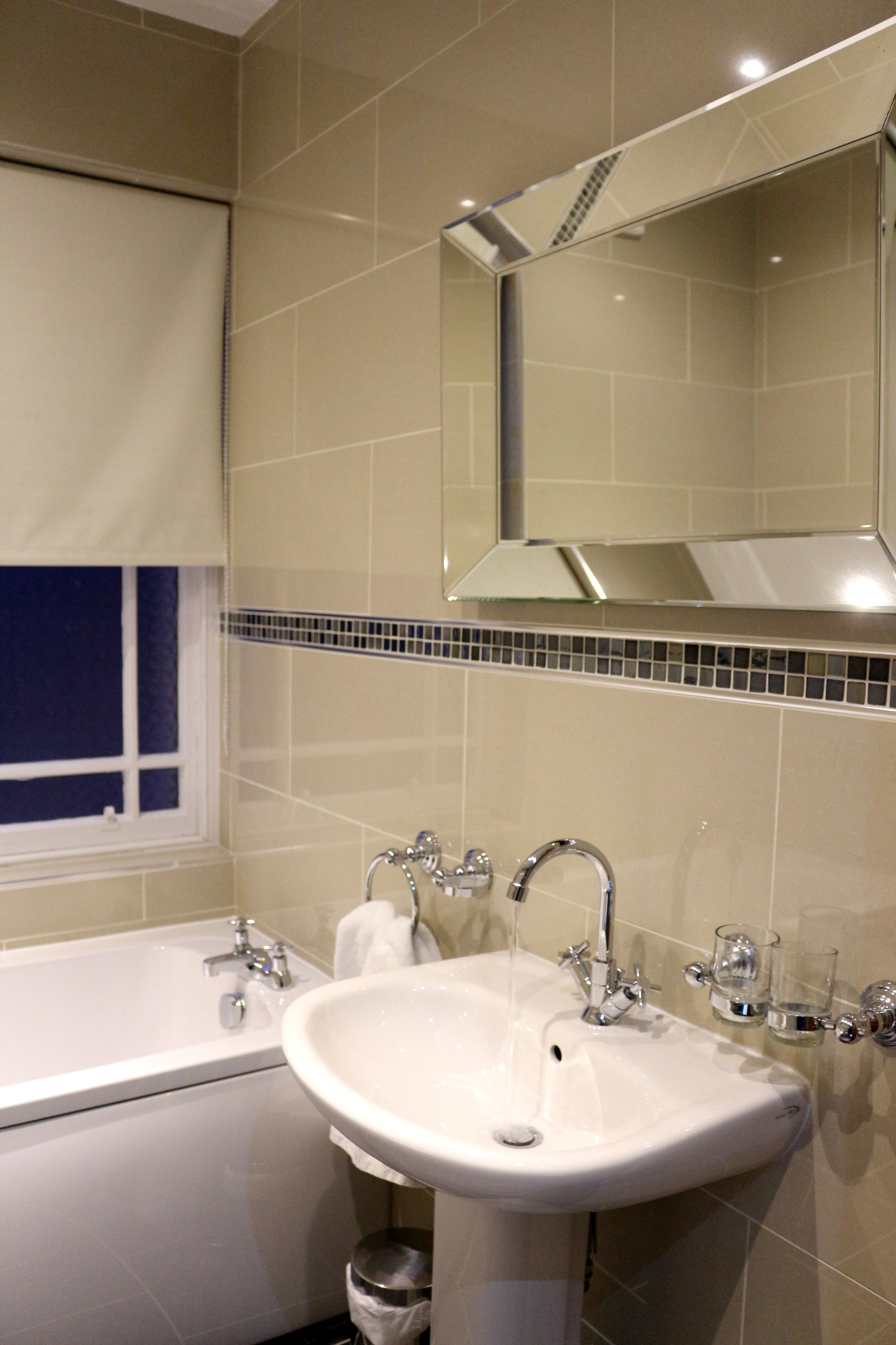 A bathroom with a bathtub, sink, and mirror.