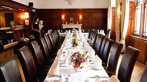 A long dining table set with white tablecloths, chairs, and floral centerpieces. - County Hotel (Stornoway)