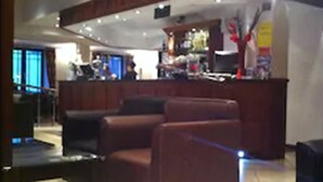 A lobby with a curved reception desk, leather seating, and a tiled floor. - County Hotel (Stornoway)