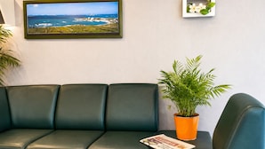Ein grünes Ledersofa mit einem Blumentopf und einem gerahmten Bild an der Wand.