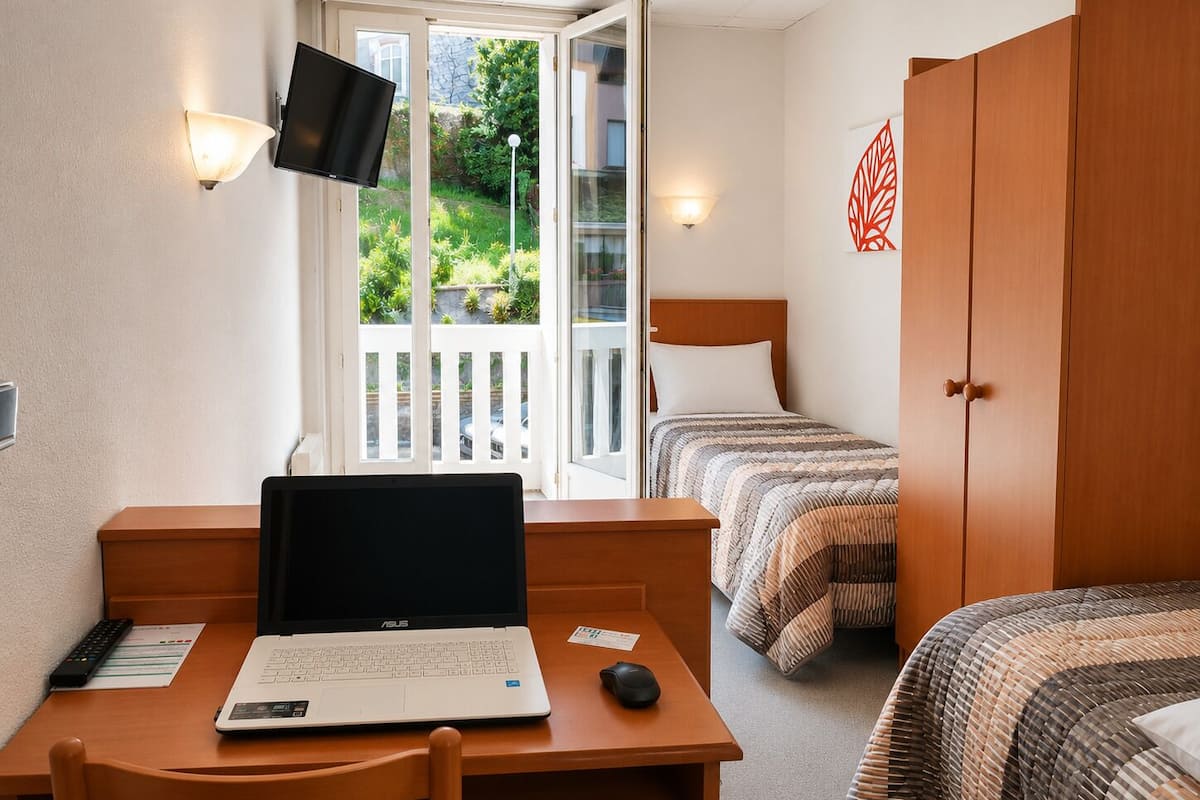 A room with a desk, a laptop, a bed, and a wardrobe.
